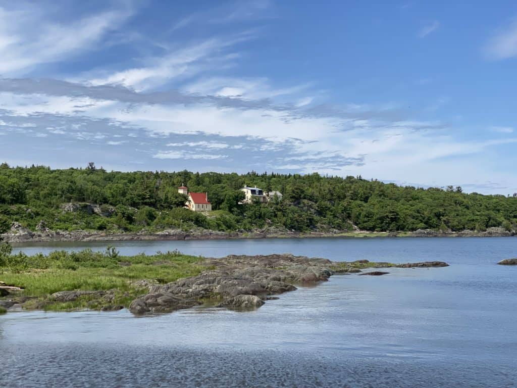 View of Grosse-Île church and another building along the coast from the water.