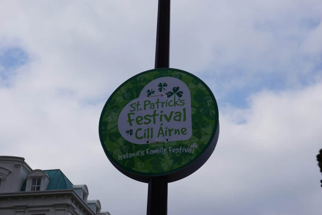 Circular green and white sign saying St. Patrick's Festival - Ireland's Family Festival in Killarney, Ireland on St. Patrick's Day.