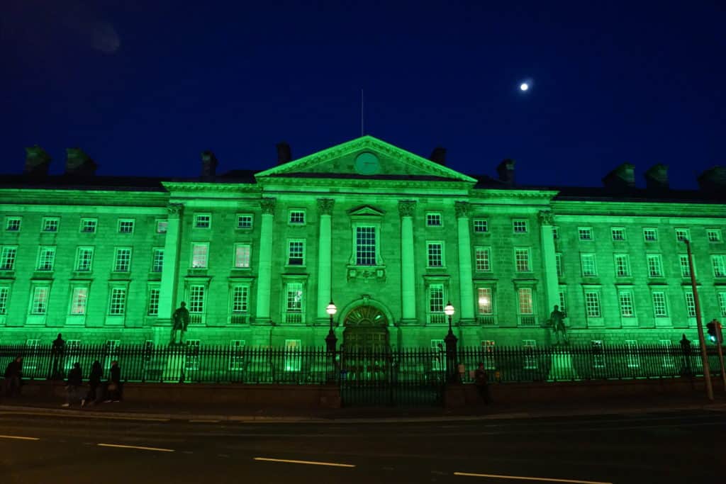 Trinity College Dublin at night with green light cast over it for St. Patrick's Day.