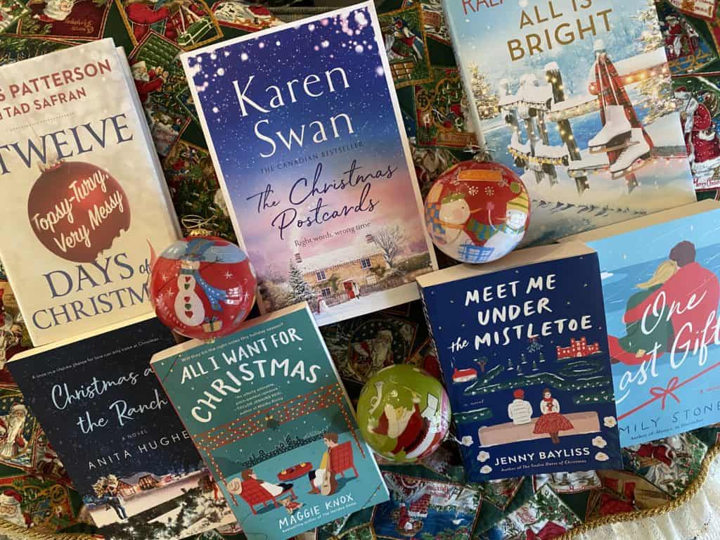 Group of 7 Christmas novels and Christmas ornaments on red and green patterned background.