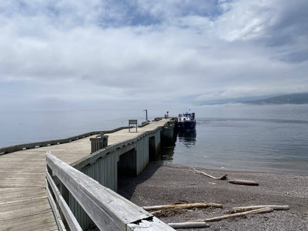 Boat docked at end of wooden pier on Bonaventure Island.