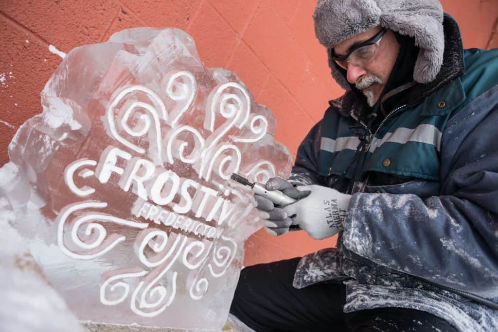 Man carving the words Frostival Fredericton in ice.
