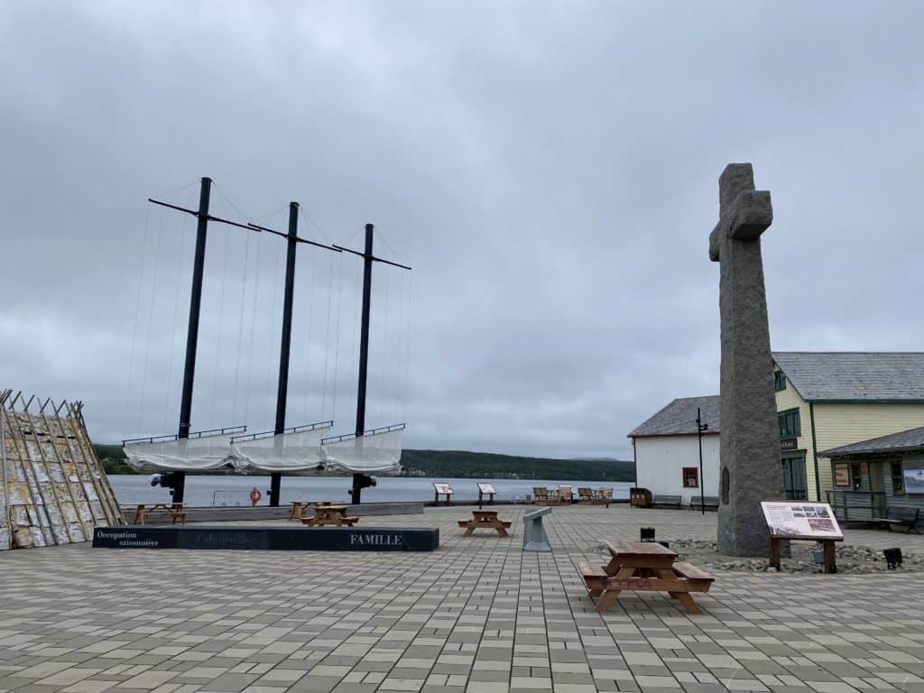 Birthplace of Canada site in Gaspe, Quebec with Mi'gmac long house, lowered ship sails, picnic tables, buildings and massive granite cross.