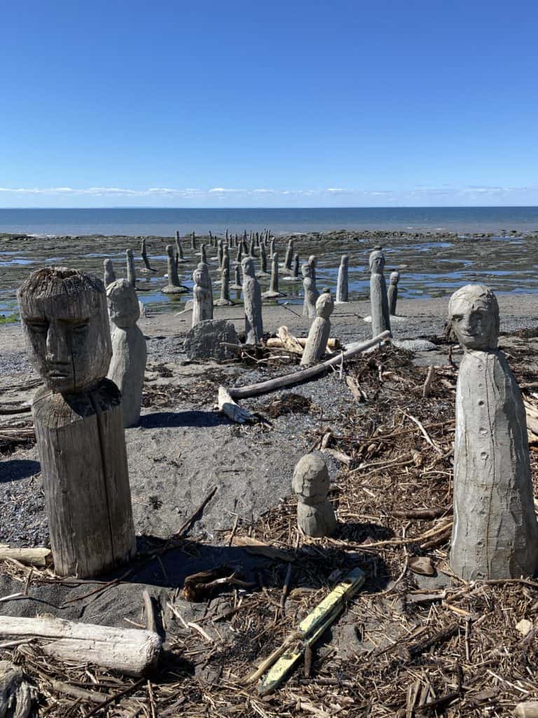 Concrete and wooden human like figures in sea - Le Grand Rassemblement by Marcel Gagnon in Sainte-Flavie, quebec.