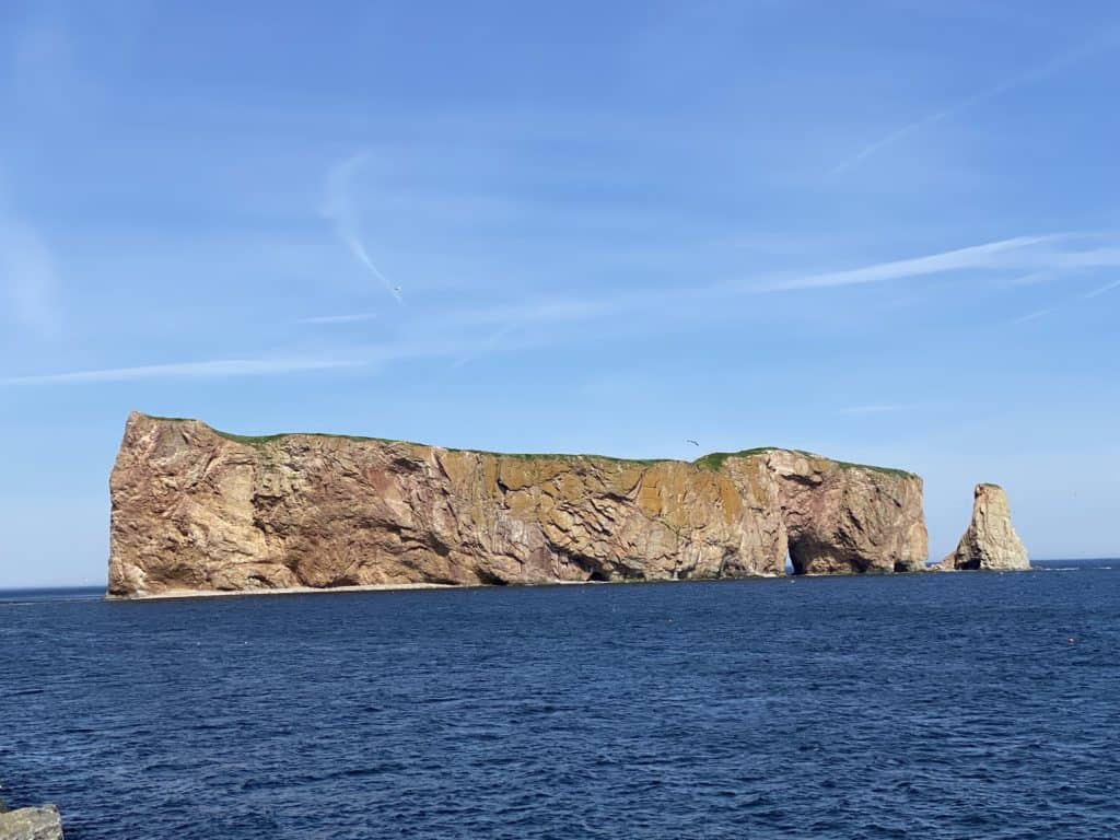 Perce Rock surrounded by water and blue sky.