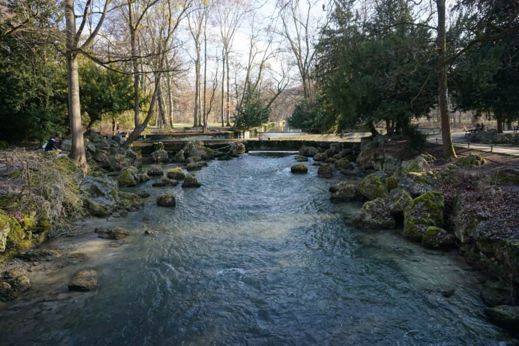Small river with rocky banks and trees in the English Garden, Munich, Germany.