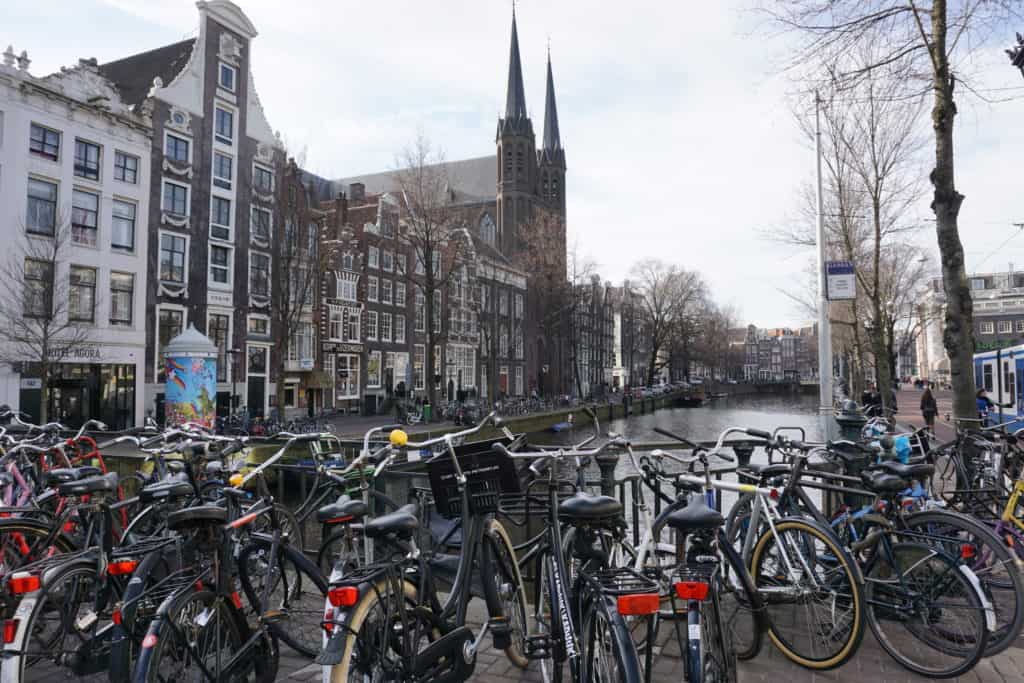 Bicycles locked to railing along canal in Amsterdam.