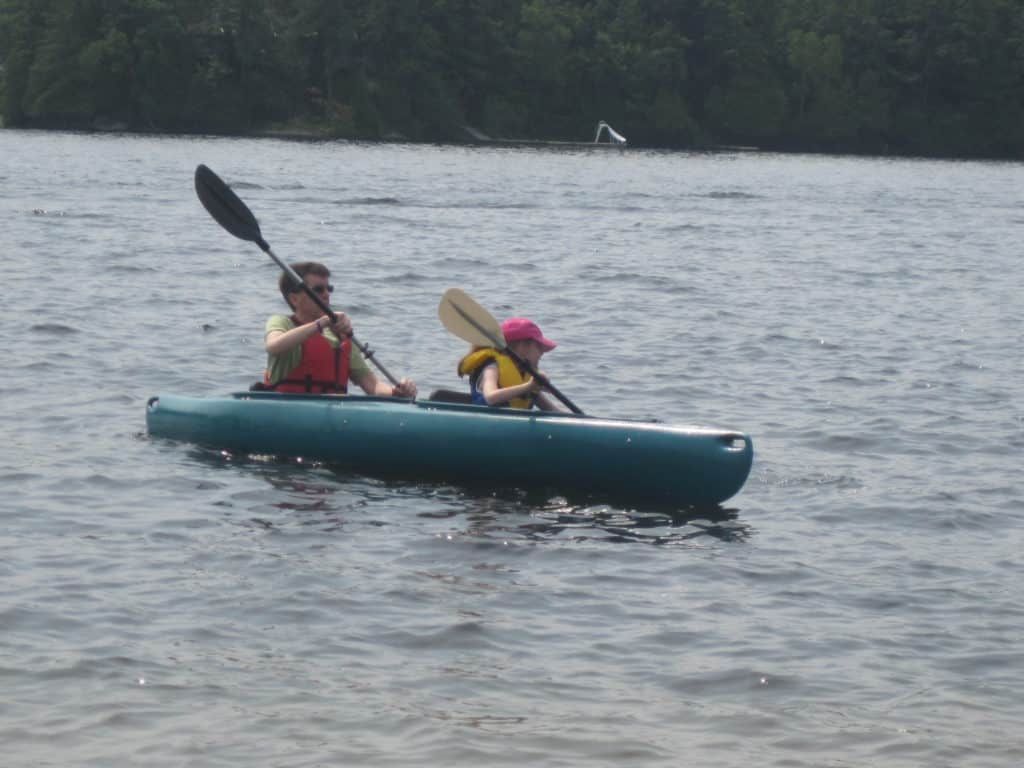 Man and young girl in kayak on lake in Ontario.