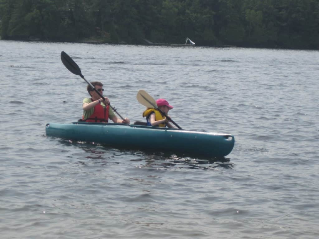 man and young girl paddling kayak in lake at rosseau muskoka.