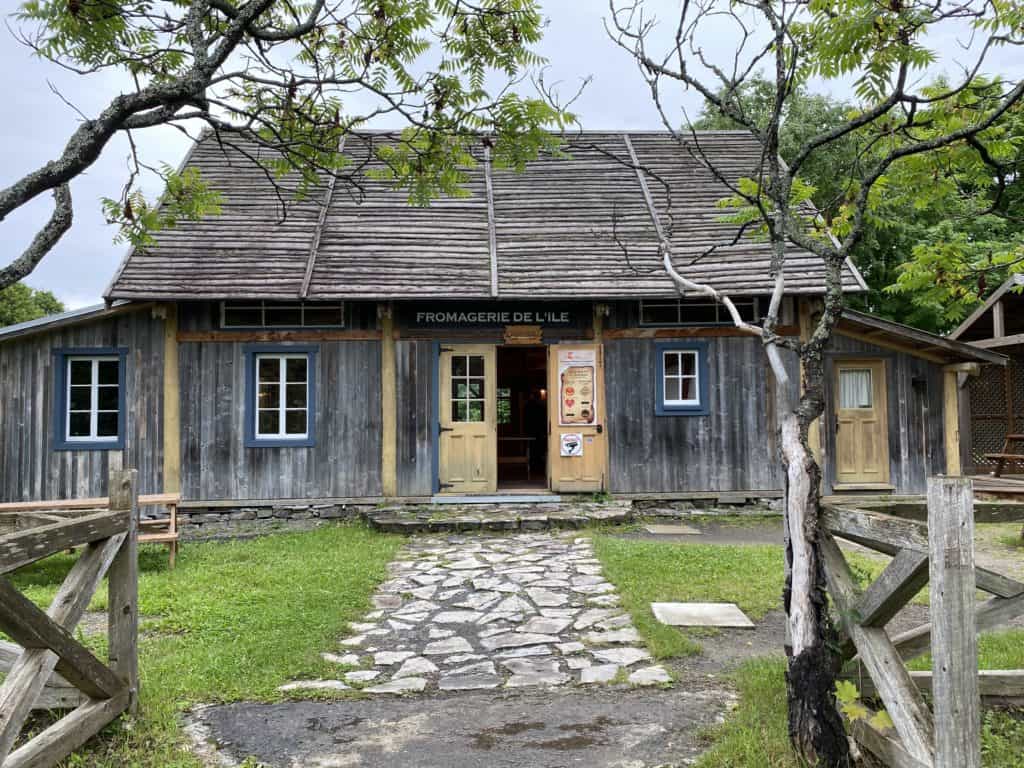 Weathered gray wood building with sign saying Fromagerie de L'Ile on Ile d'Orleans near Quebec City.