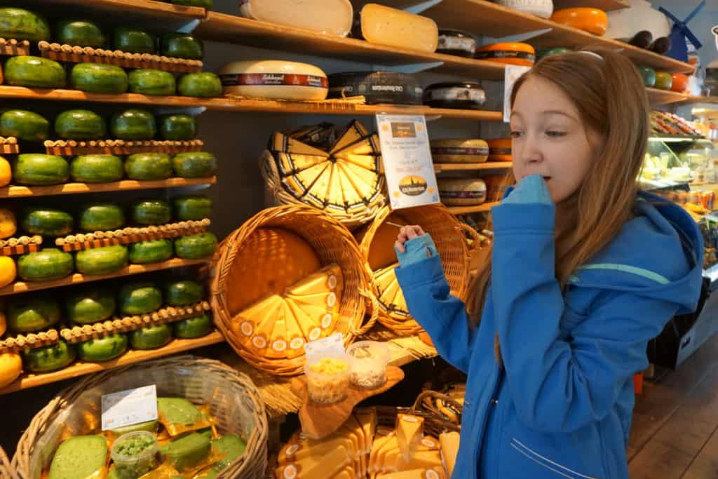 Young girl in blue coat sampling cheese in a cheese shop in Amsterdam.