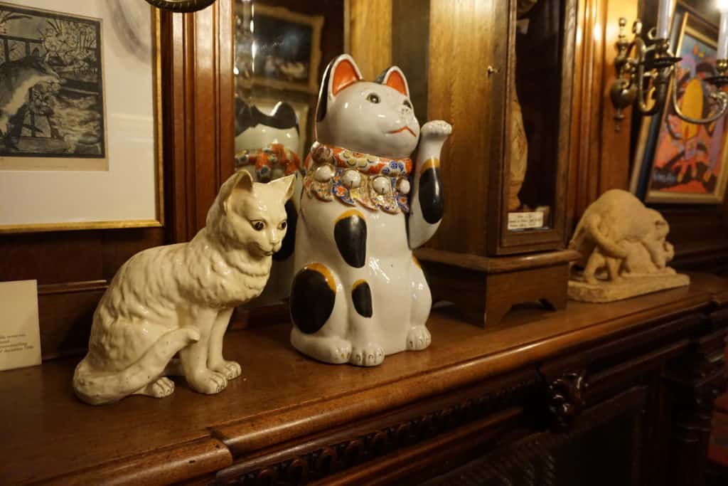 Porcelain cats on display on shelf at KattenKabinet in Amsterdam.