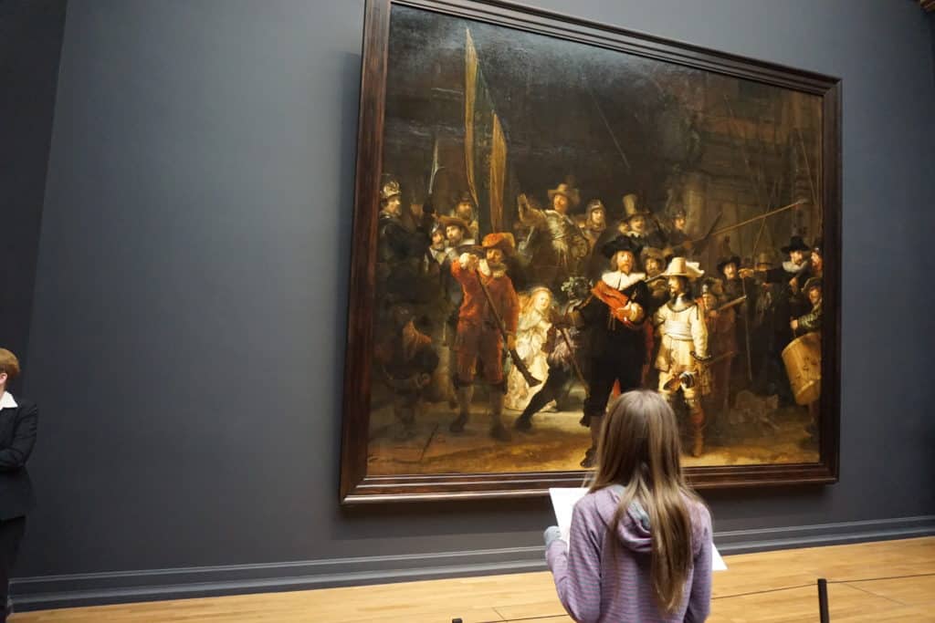 Young girl looking at Rembrandt's The Night Watch at the Rijksmuseum in Amsterdam.