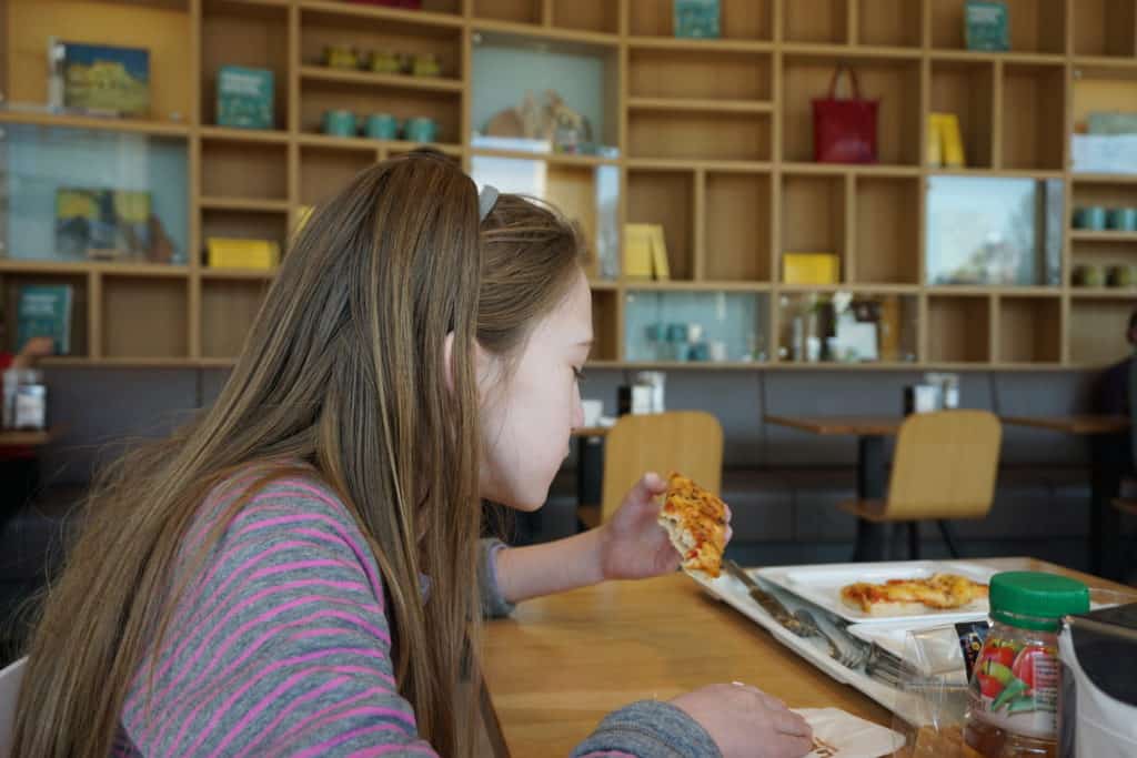Young girl eating a slice of pizza at table in the cafe at Van Gogh Museum in Amsterdam.