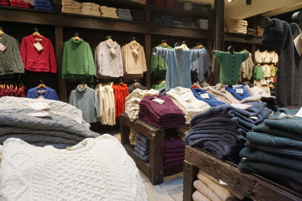 Woolen shop in Dublin with colourful wool sweaters hanging and stacked on tables.