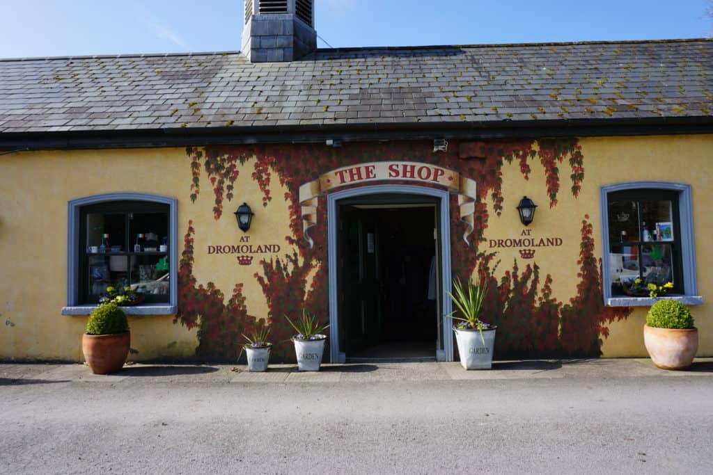 Yellow coloured shop with vines around door and plants out front - sign over door saying The Shop.