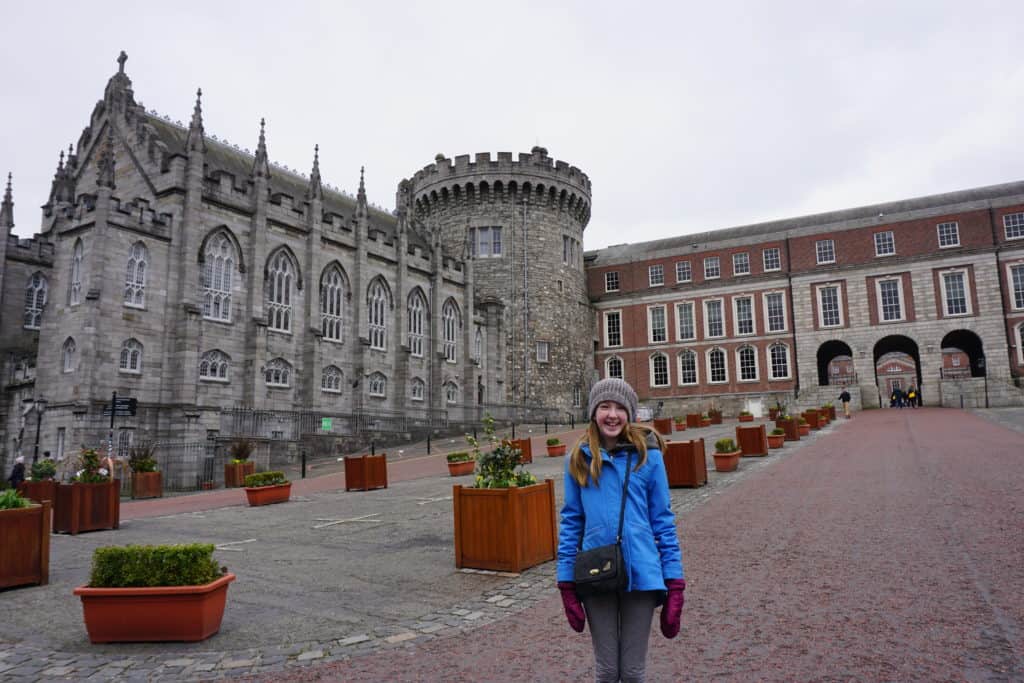 Young girl in blue coat and hat standing outside Dublin Castle.