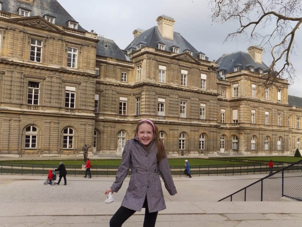 Young girl posing in front of Luxembourg Palace in Luxembourg Gardens in Paris.