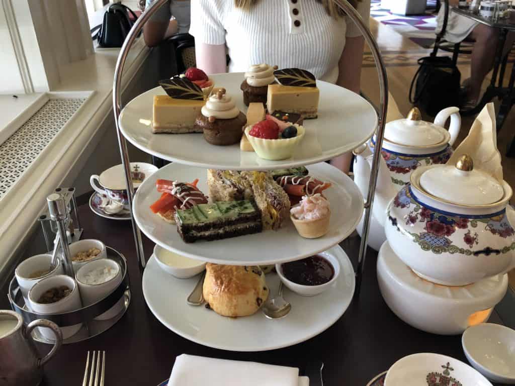 Three tiered tray of food and pots of tea sitting on table at high tea at Fairmont The Empress.