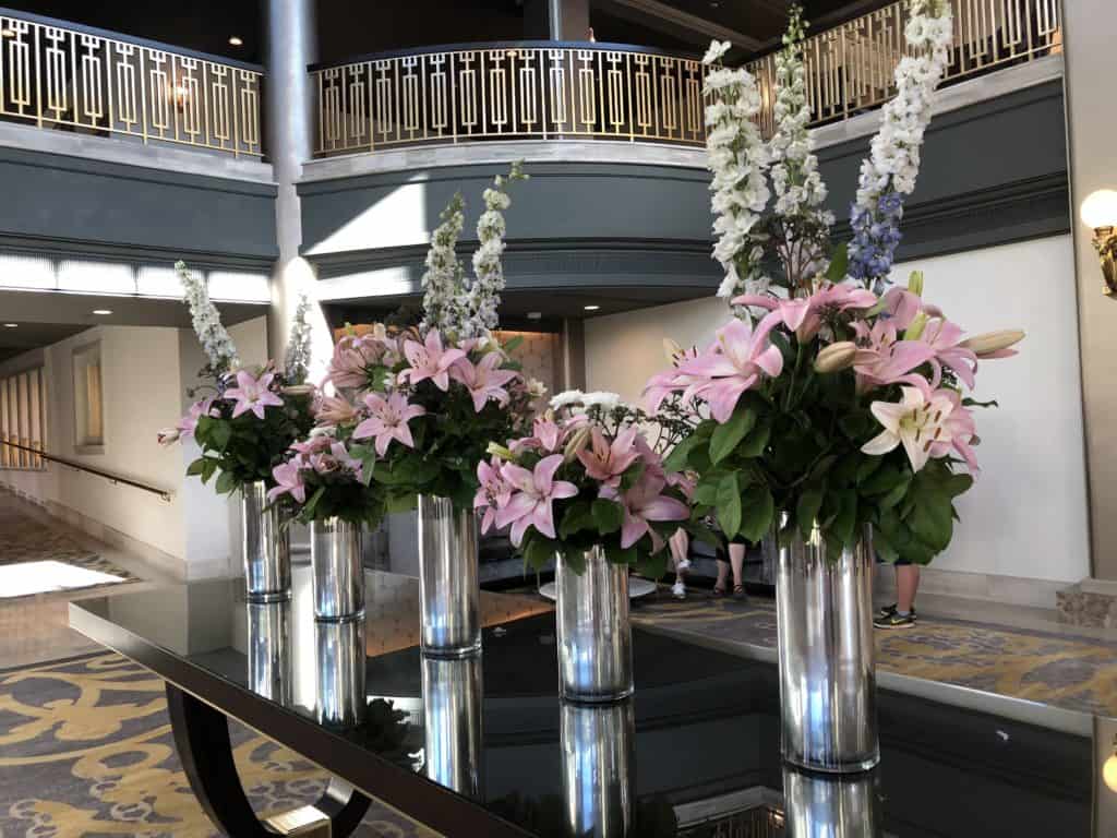 Five vases of pink lilies and white flowers on display on a table in the lobby of the Fairmont Empress in Victoria, British Columbia.