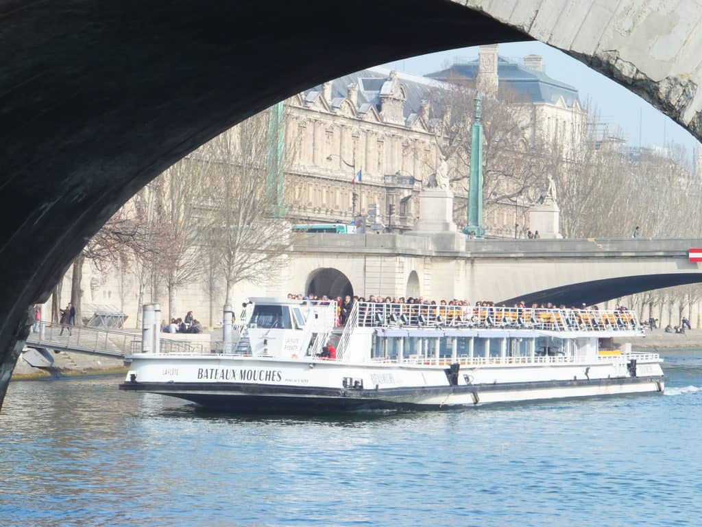 Bateaux Mouches boat on the Seine River in Paris coming through the opening of a bridge.