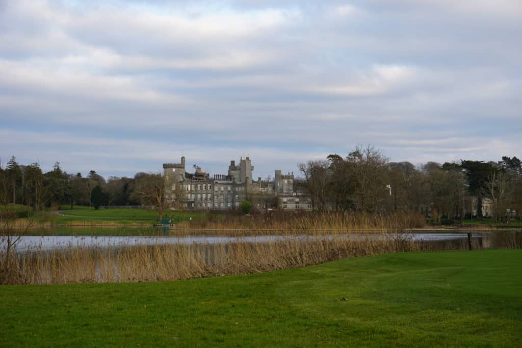 Dromoland Castle viewed from the landway with water and grasses in foreground.