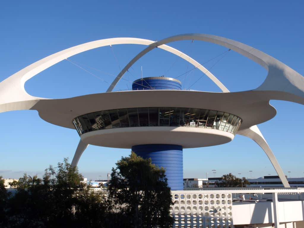 Theme Building's Iconic Restaurant rise between terminals at Los Angeles International Airport on a clear day.