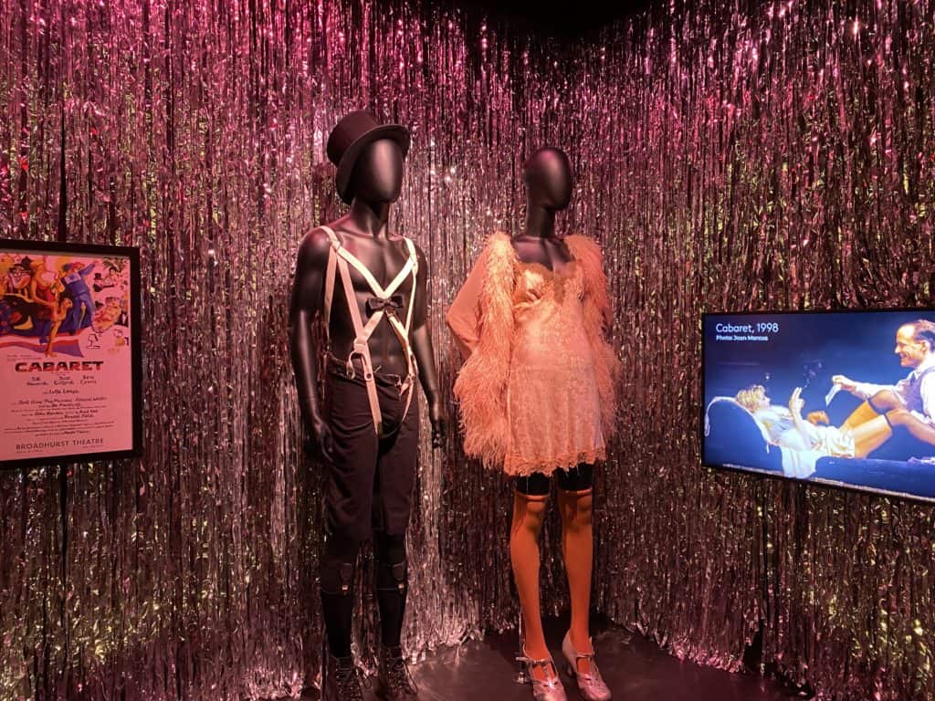 Display of costumes worn by the MC and SallyBowles in Cabaret with glittery tinsel hanging behind.