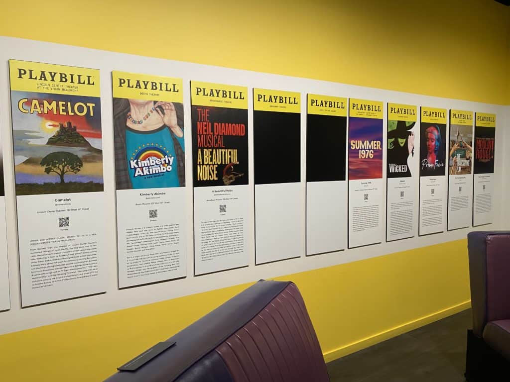 Row of Playbills from Broadway shows mounted on yellow wall at the Museum of Broadway in New York City.