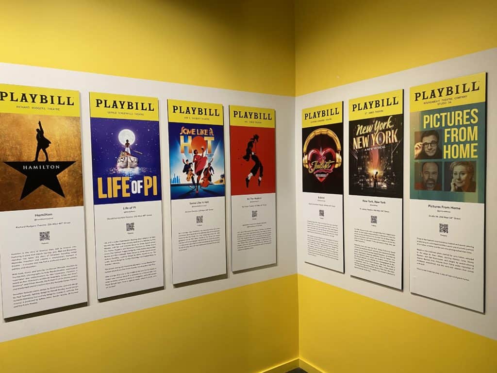 Broadway Playbills mounted on yellow wall at the Museum of Broadway in New York City.