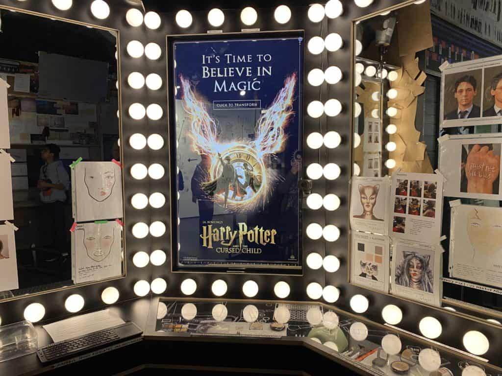 Makeup table with lights and poster of Harry Potter and the Cursed Child in middle, with makeup sketches for Cats and other shows displayed.