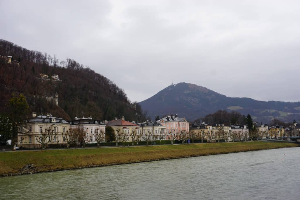 Buildings along the river and mountains in the background at Rudolfskai in Salzburg, Austria.