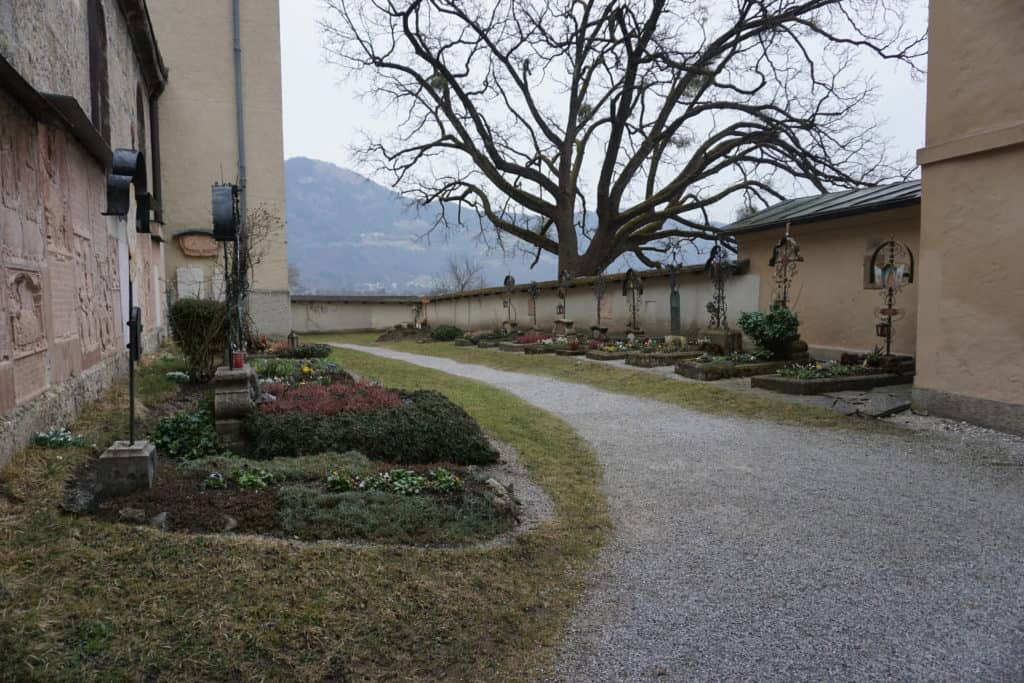 Small cemetery at Nonnberg Abbey with mountains in the background.