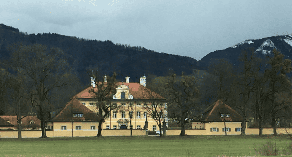 Exterior of Schloss Frohnburg (yellow with dark brown roof) in Salzburg, Austria.