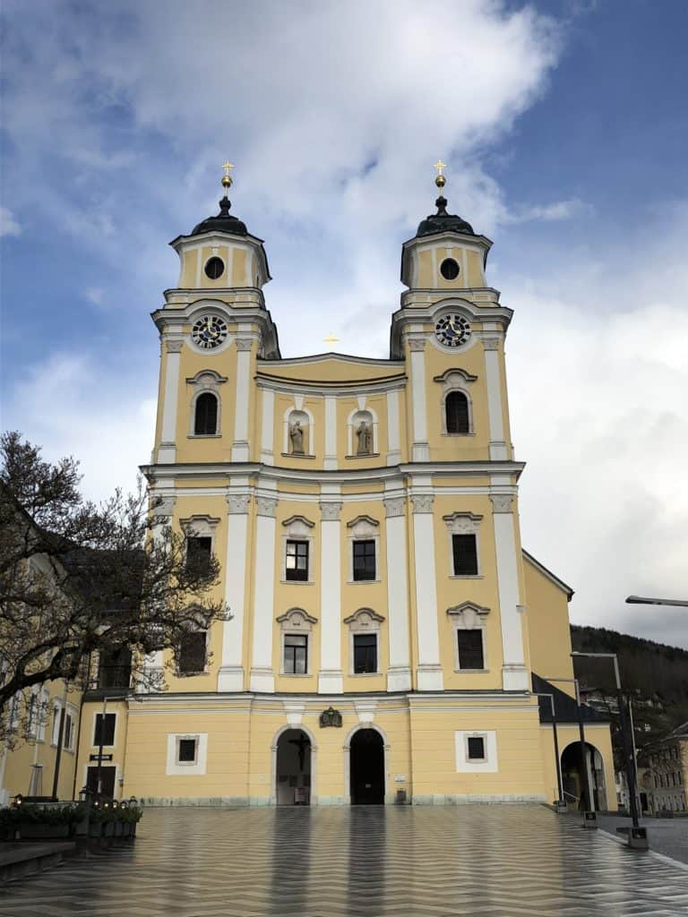 Yellow and white cathedral with two clock towers in Mondsee, Austria near Salzburg.