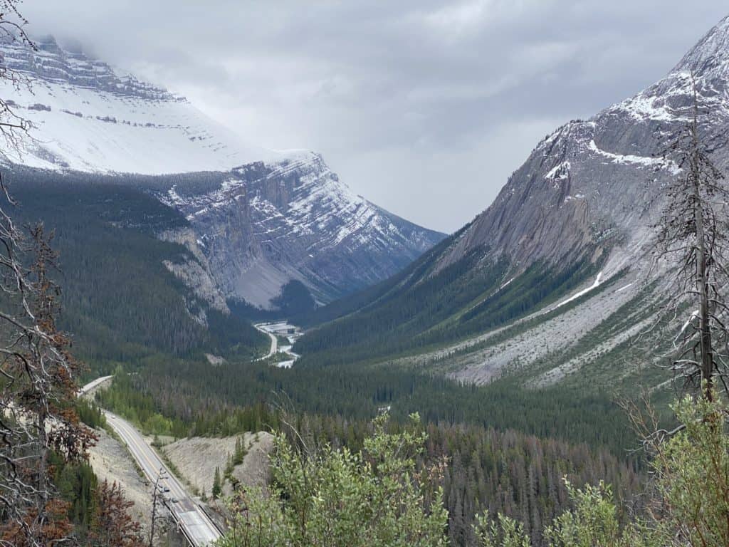 Icefields Parkway in Alberta, Canada - snow-topped mountains, forest with road running through.