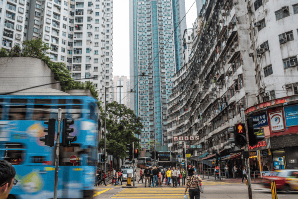 Quarry Bay in Hong Kong - street with large buildings, traffic and pedestrians.