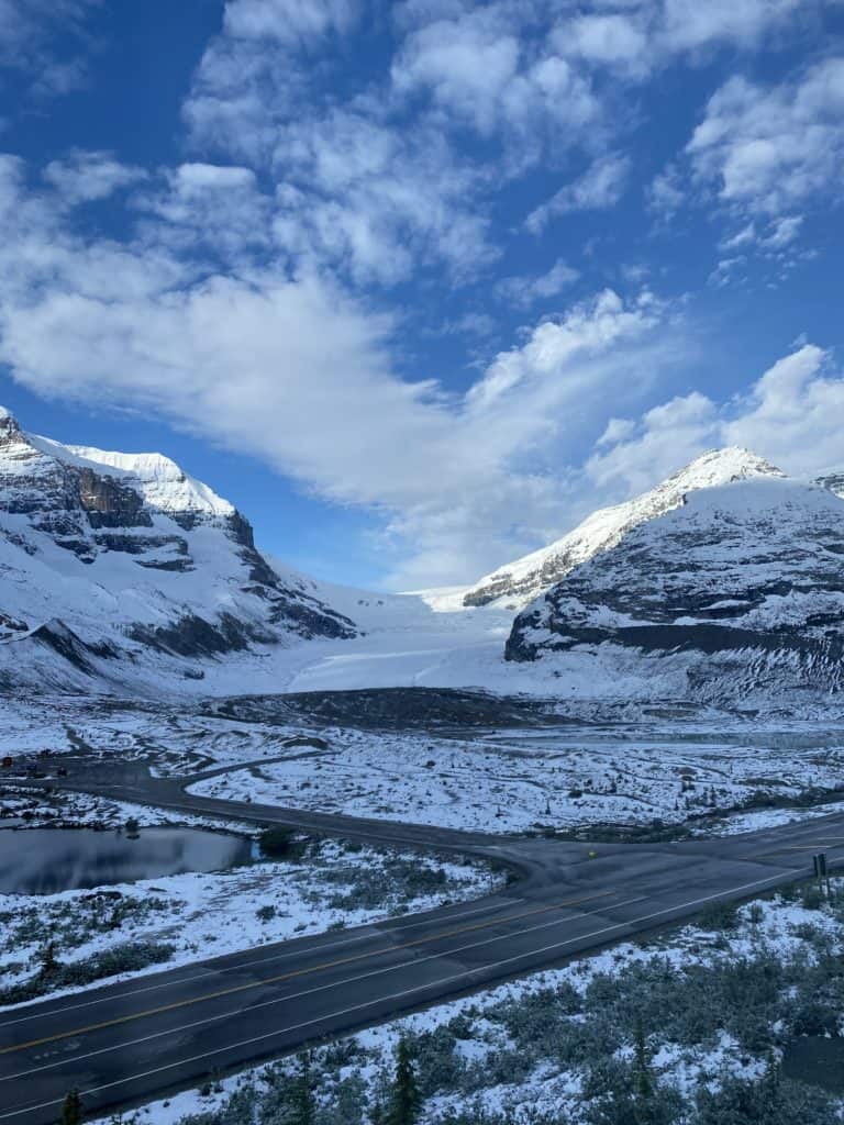 View of blue sky with snow-capped mountains and Athabasca Glacier from the window of room at Glacier View Lodge.