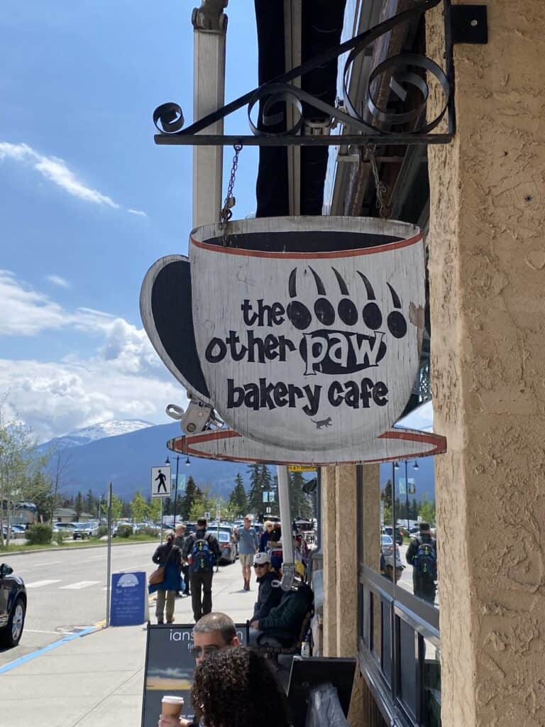 Sign for The Other Paw Bakery Cafe on street in Jasper.