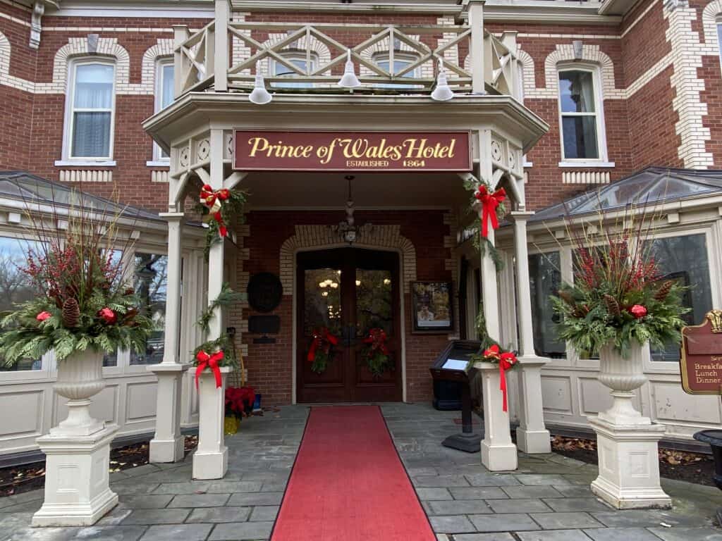 Entrance to the Prince of Wales Hotel - red carpet, urns with holiday greenery and greenery and red bows wrapped around columns.
