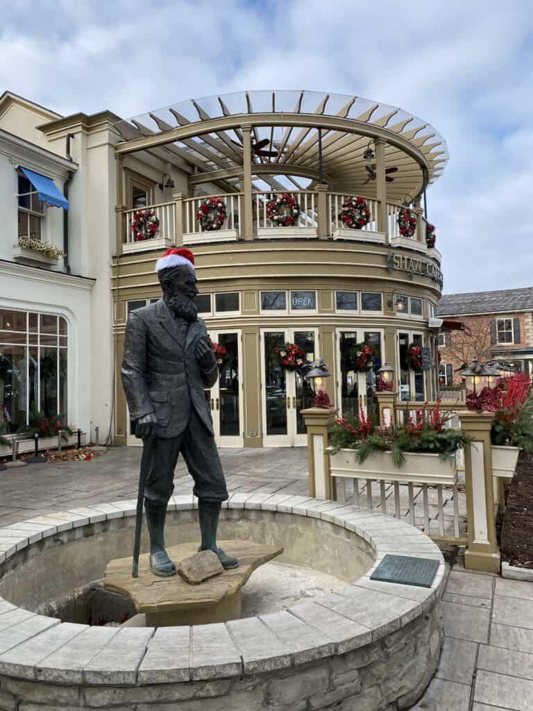 Statue of George Bernard Shaw wearing Santa hat outside Shaw Cafe decorated with wreaths for the holiday season.