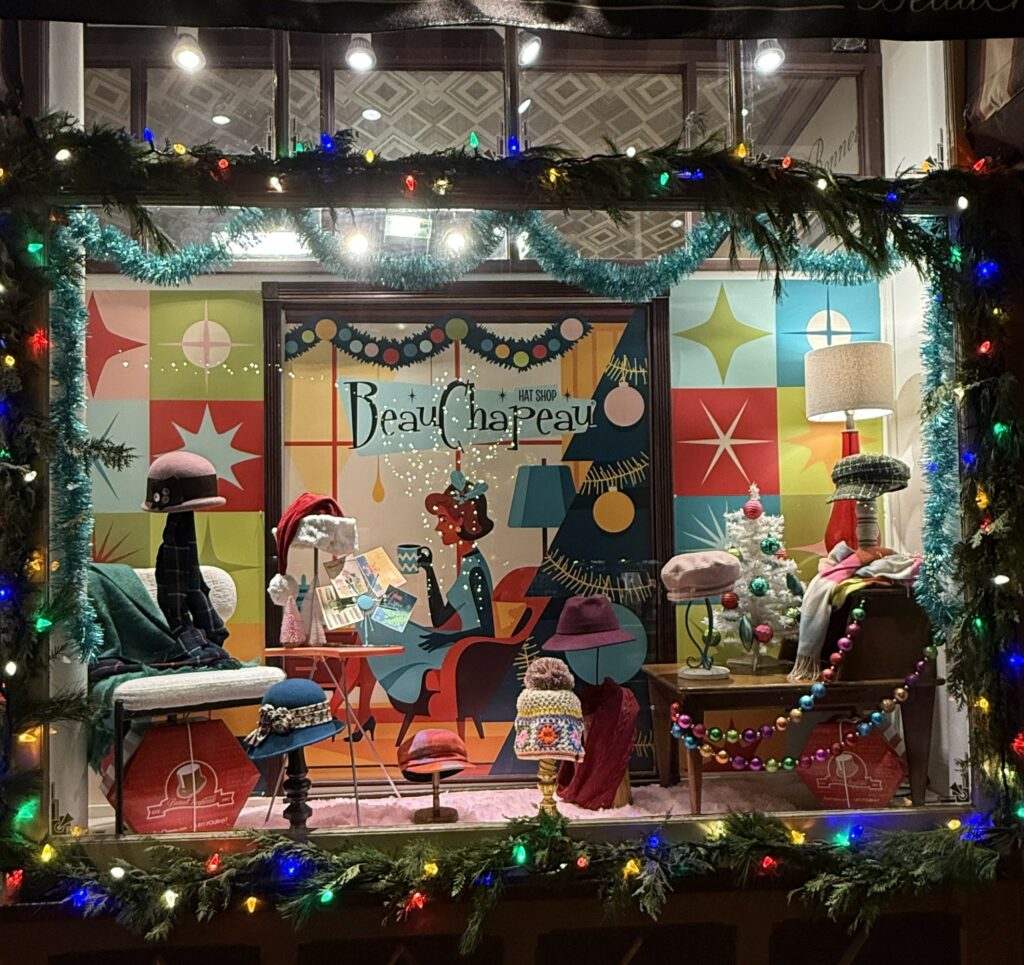 Window at Beau Chapeau shop in Niagara-on-the-Lake decorated for Christmas and lit up at night.