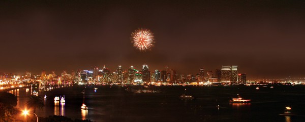 Fireworks over San Diego skyline and parade of boats with lights in the bay.