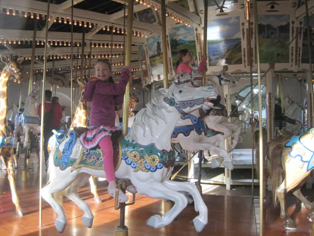 Young girl riding carousel at Seaport Village in San Diego.