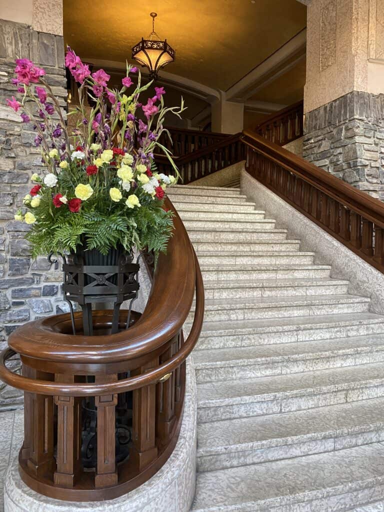 Stone staircase with arrangement of yellow, red and white roses at the bottom in the lobby of the Fairmont Banff Springs Hotel.