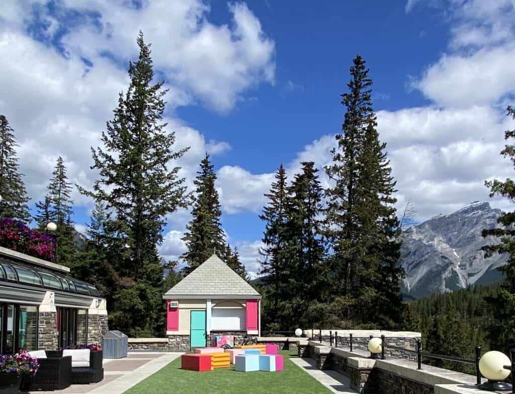 Multi-coloured ice cream bar and seating on outdoor terrace at Fairmont Banff Springs with trees and mountains in background.