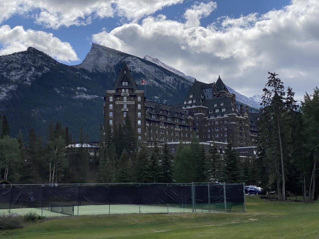 Tennis courts with Fairmont Banff Springs hotel and mountains in background.