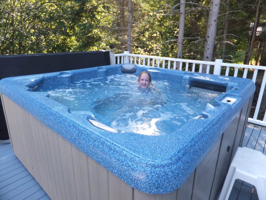 Young girl sitting in hot tub on cottage deck at Kindred Spirits, Cavendish, Prince Edward Island.