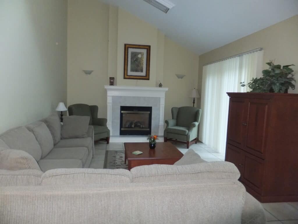 Long L shaped couch, table, gas fireplace with two wingbacked chairs on either side, tv unit in living area of 3 bedroom cottage - Kindred Spirits.