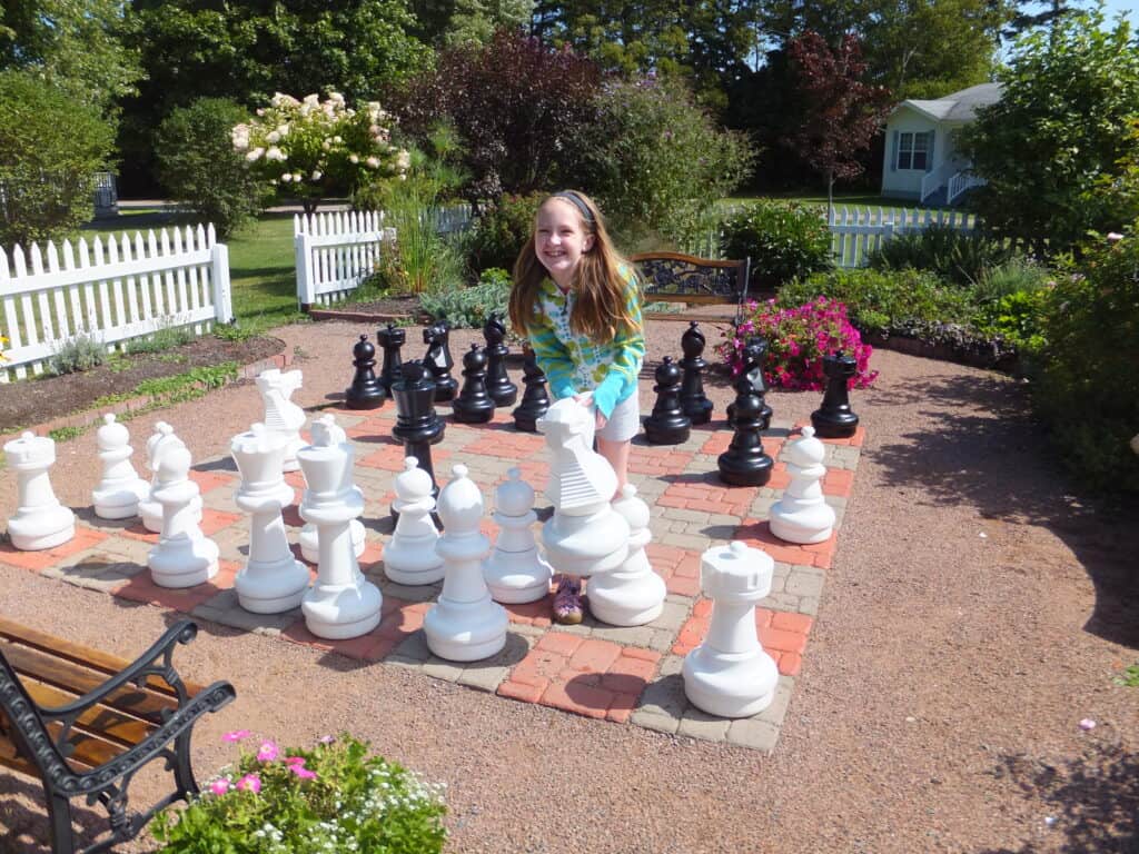 Young girl with giant chess board in garden at Kindred Spirits in Cavendish, Prince Edward Island.